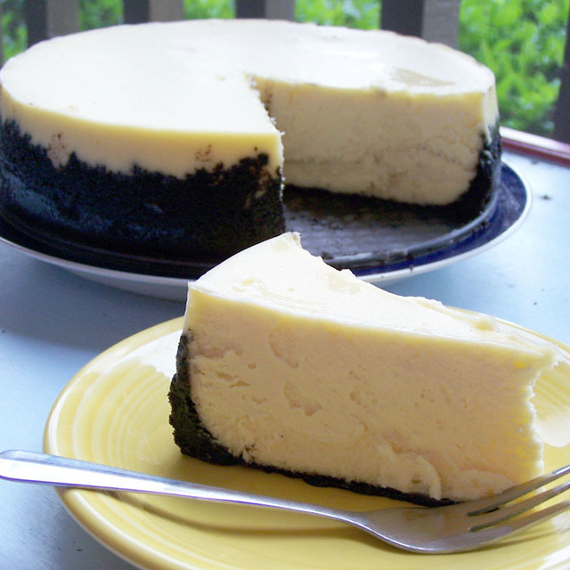 A cheesecake, with a slice taken from it on a plate nearby